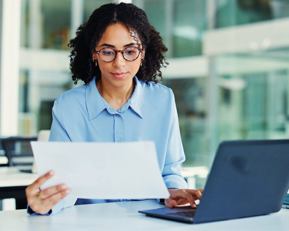 Technology decision-maker reviewing a report beside a laptop in a modern office