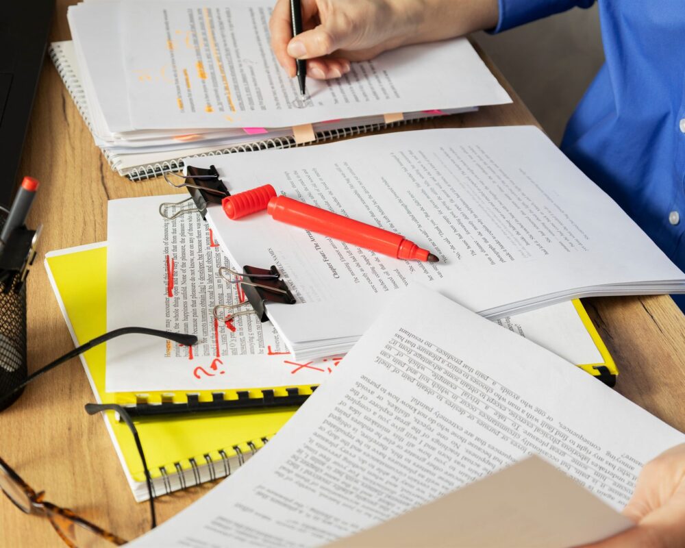 Editor marking up printed research drafts with handwritten corrections